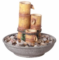 An indoor fountain made to look like bamboo shoots standing in a bowl of stones.